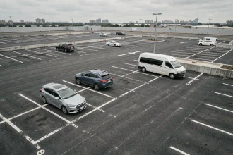 Vue aérienne d'un parking urbain avec des places délimitées accueillant différents types de véhicules de tailles variées