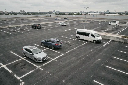 Vue aérienne d'un parking urbain avec des places délimitées accueillant différents types de véhicules de tailles variées